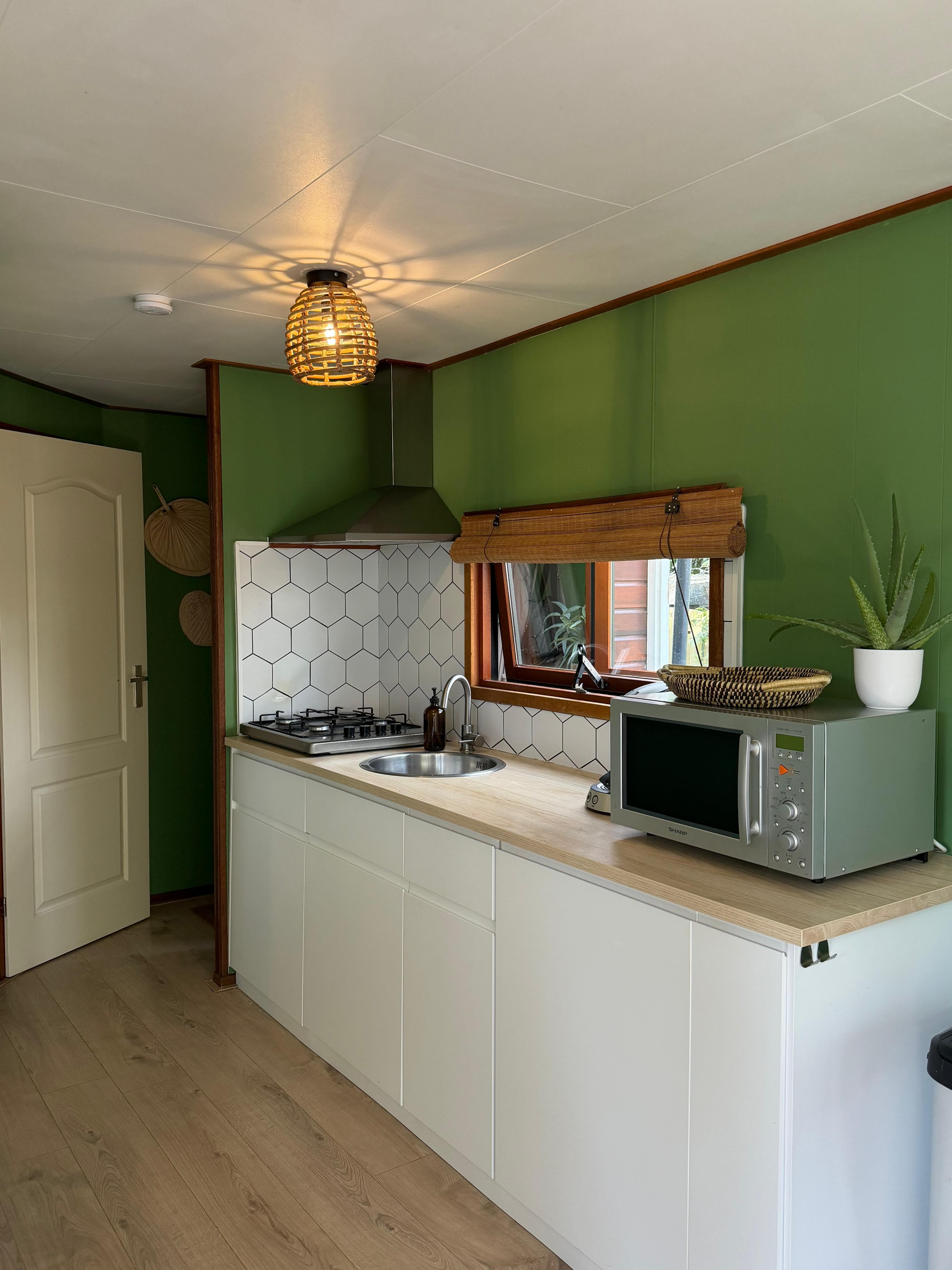 Keuken van Bosbreak met groene wand en witte kastjes